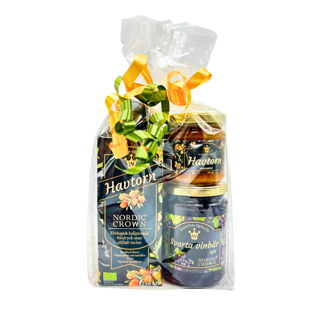 Presentpåse i cellofan med gula, orange och gröna band. I påsen syns en kartong havtornsdryck 750 ml, en burk havtornsmarmelad och en burk svartvinbärssylt från Nordic Crown.