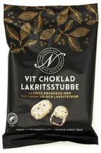 Svart påse från Narr Chocolate med guldfärgade kakaoblad och texten Vit choklad lakritsstubbe, med bild på två lakritsbitar dragerade med vit choklad, mot vit bakgrund.